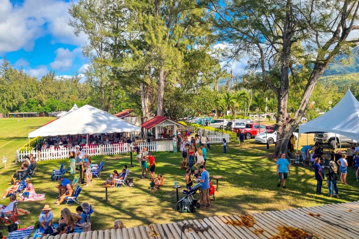 Outdoor event with people, tents, and trees on a sunny day.