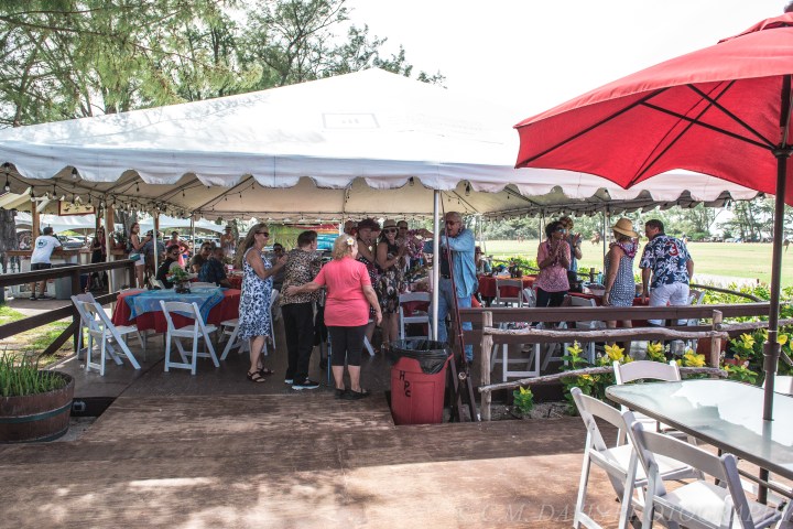 People socializing under a white tent with tables and chairs outside.